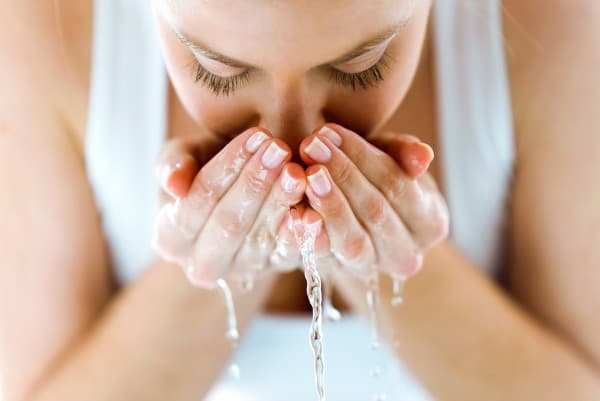 水をはねさせながら顔を洗う外国人の若い女性